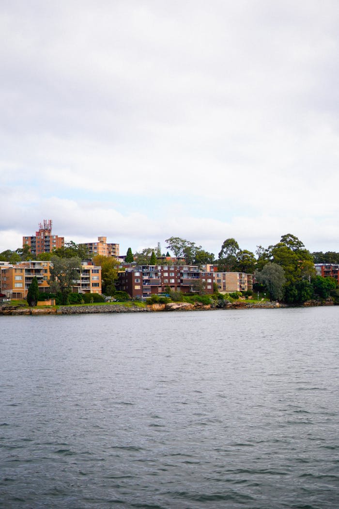 A serene view of buildings by the water edge under a cloudy sky.